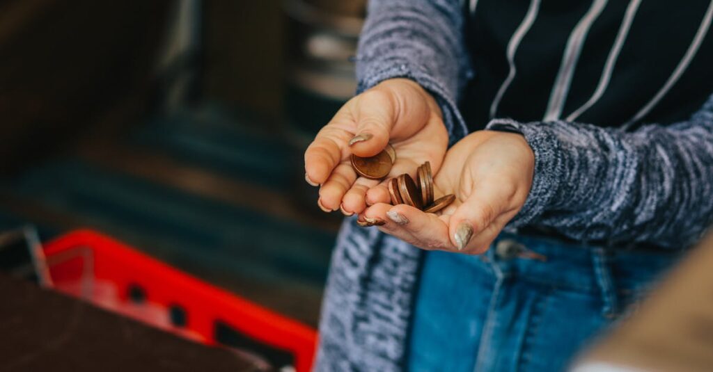 Close-up of a person's hands holding loose change at a Prague market.