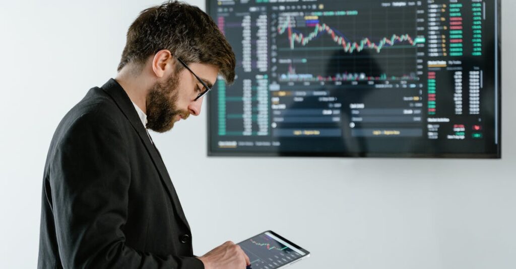 Professional man using tablet in front of cryptocurrency trading screen indoors.